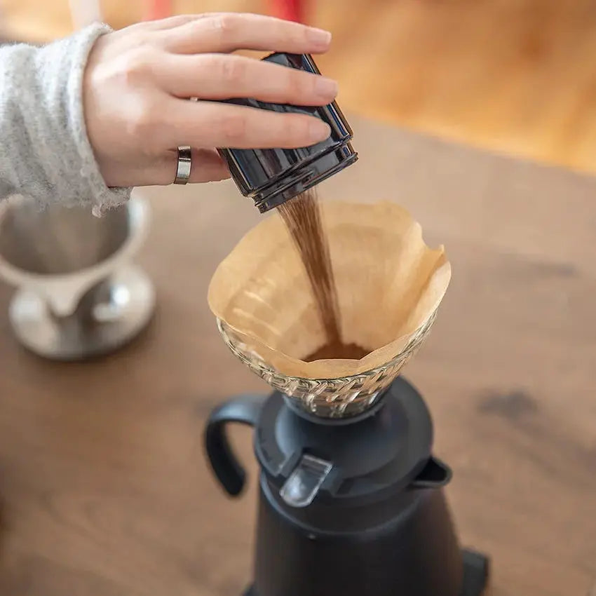 Pouring ground coffee into a Hario V60 Coffee Filter Paper Size 01 Unbleached